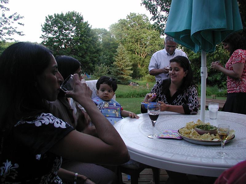 P7040004.JPG - Devika trying to feed Rohan. Rohan is more interested in what Aditee is drinking.