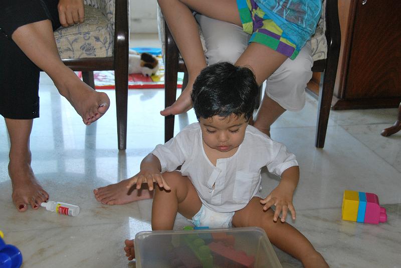 DSC_0330.JPG - Rohan with a toys in front of him and a bunch of legs in the background.