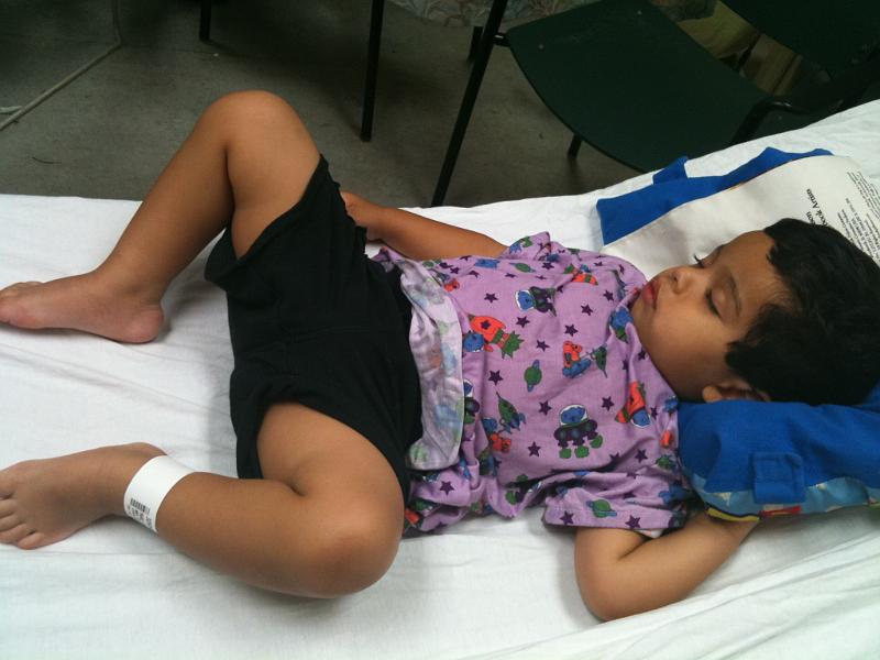 IMG_0222.JPG - On the night of May 17 Rohan developed a fever that hovered between 103 and 105 the whole night. The next morning we took him to the pediatrician. The doctor said he was marginally dehydrated. So we took him to thepediatric emergency room. A few hours later they told us that in addition to ear infection he had pneumonia and a throat infection. His blood sugar was low, the white blood count was high and he was dehydrated. He was hooked to an ivy to pump fluid, antibiotic and sugar into him. Here he is in the emergency room bed.